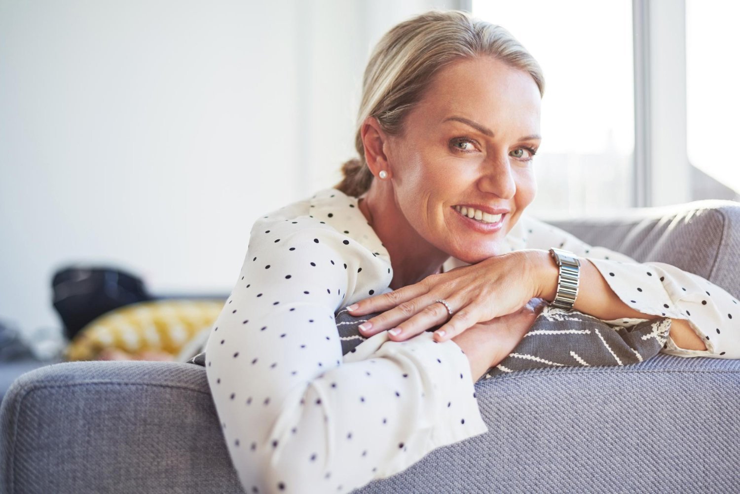 Smiling middle-aged woman relaxing on a couch with arms folded